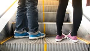 two pairs of feet on escalator going up