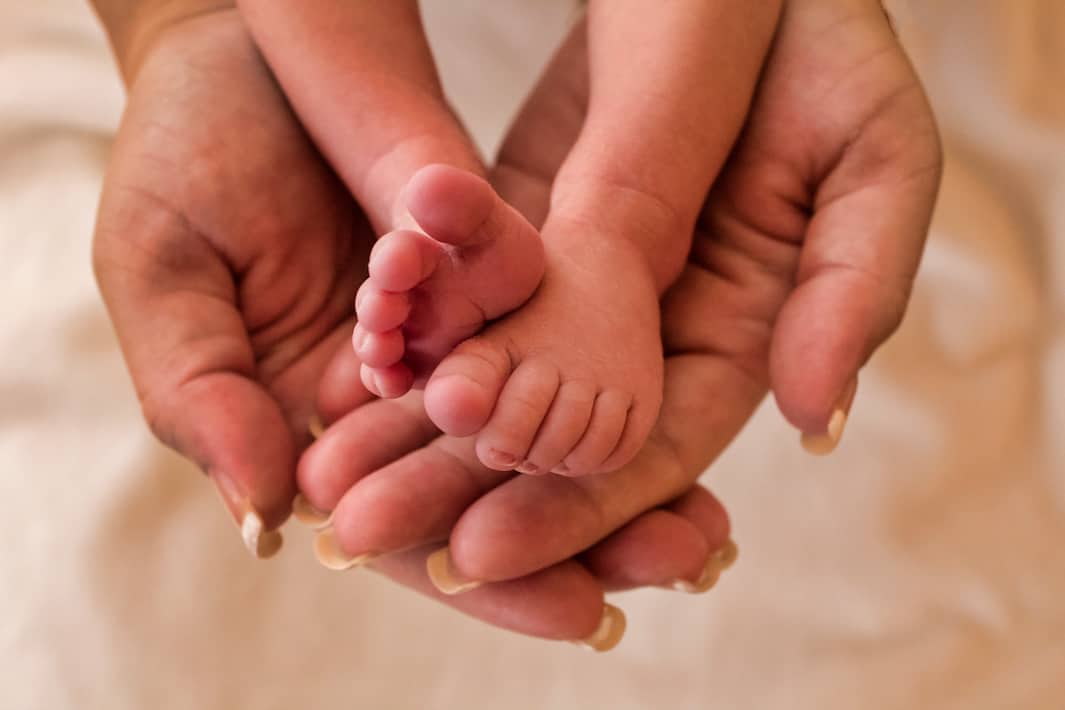 Feet of newborn baby in the hands of the mother