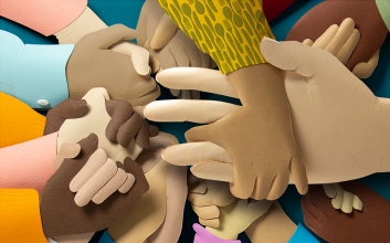 Paper illustration of many hands laced together in prayer