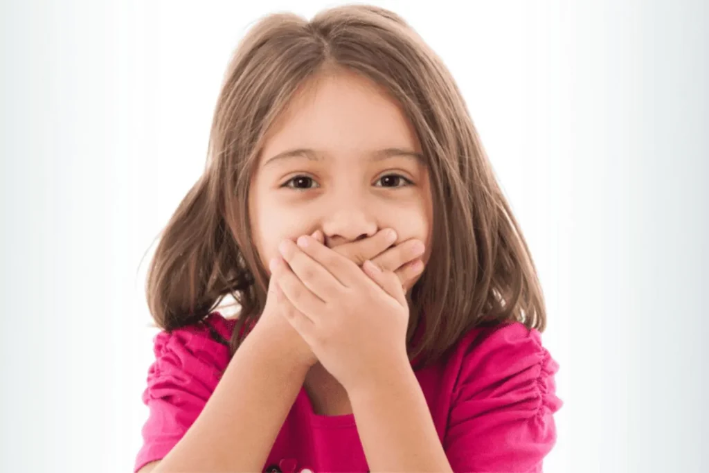 Little girl with her hands over her mouth