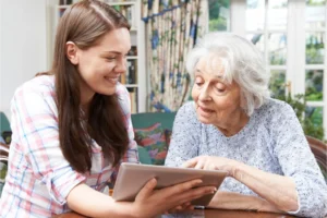 Teen girl helping elderly woman learn technology