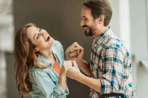 A joyful couple laughs and holds hands, representing the importance of psychological flexibility in marriage to strengthen their bond and adapt to challenges.