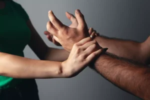 Photo of a woman's arms holding off a man's arms in a struggle.