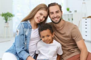 Happy couple with adopted African-American boy at home