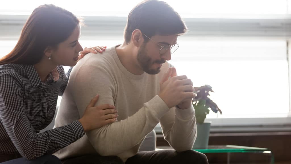 couple-sit-on-sofa-woman-comforting-man