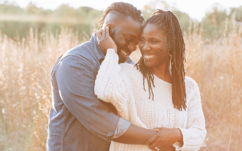 laughter in marriage - A husband and wife laugh and embrace in a field