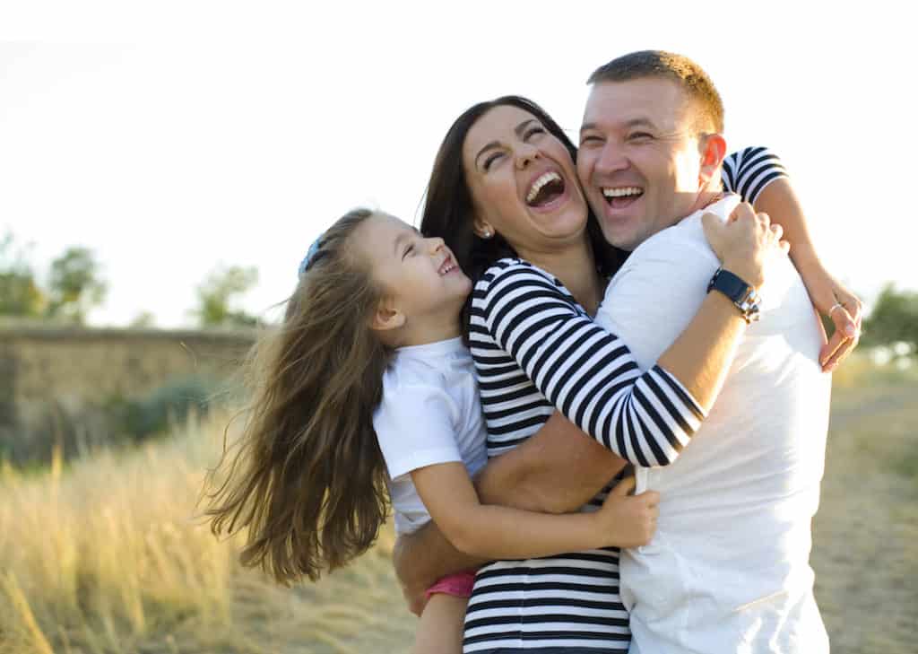 Young happy family frolics outdoors in summer