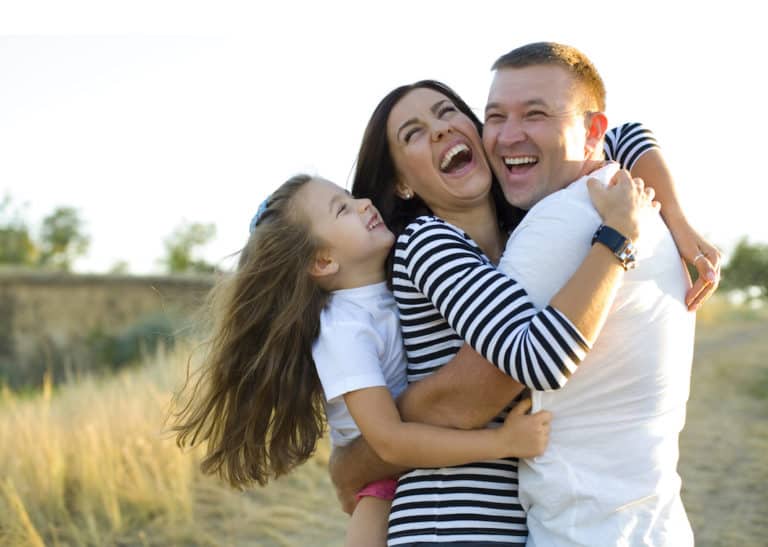 Young happy family frolics outdoors in summer