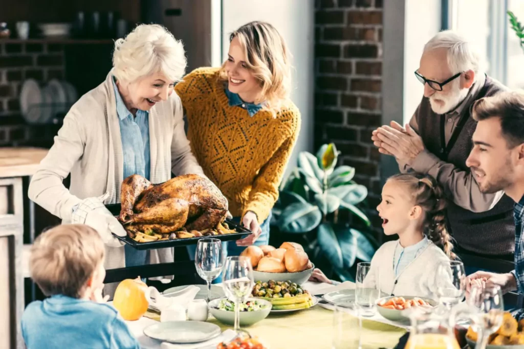 Thanksgiving dinner with grandma presenting the family with a cooked turkey