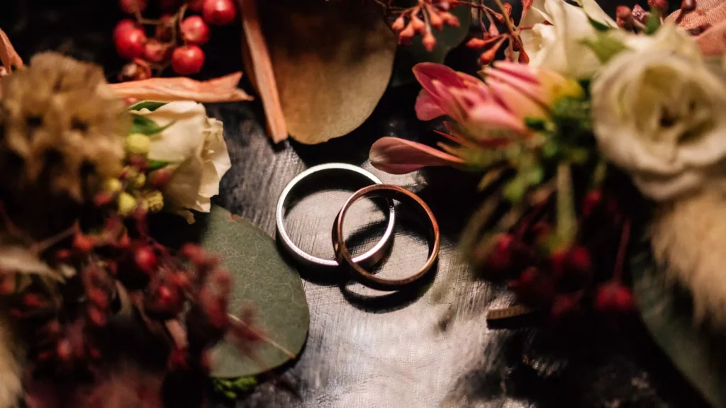 Photo of traditional wedding rings surrounded by flowers, representing the marriage vows made on the wedding day.