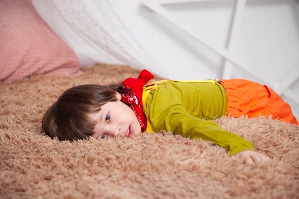Child lying on bed looking at camera with defiance