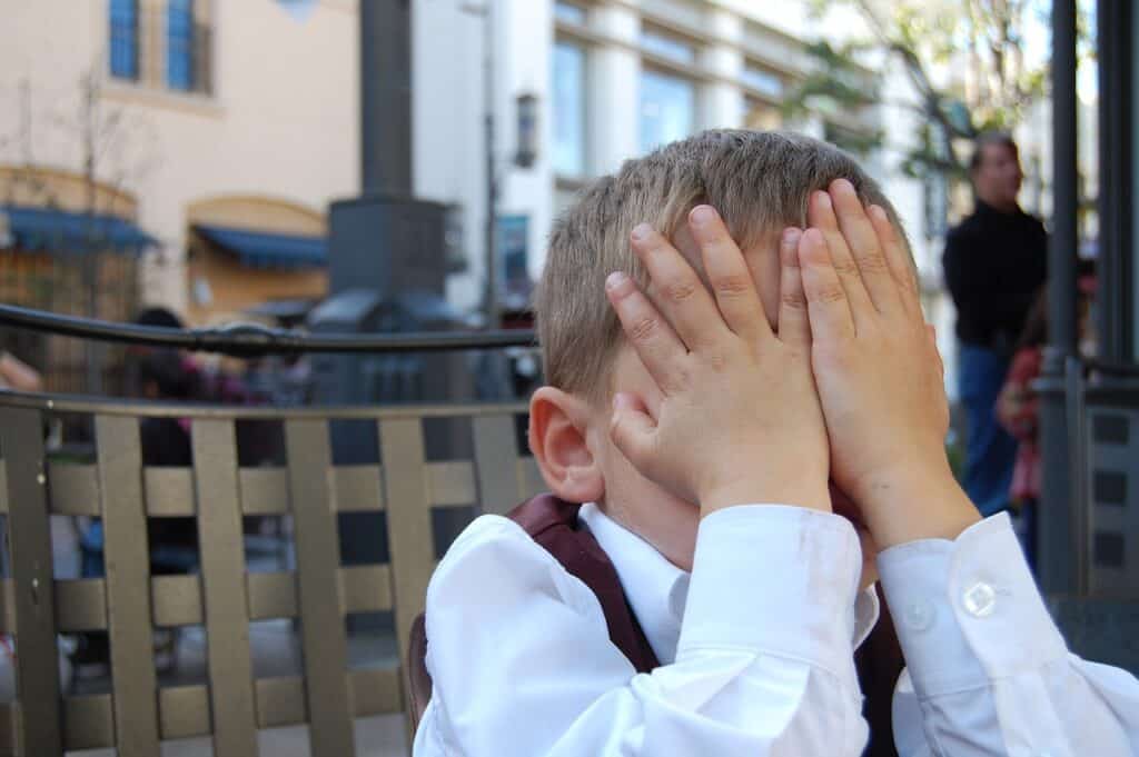 Preschool boy covering face so he can't see.
