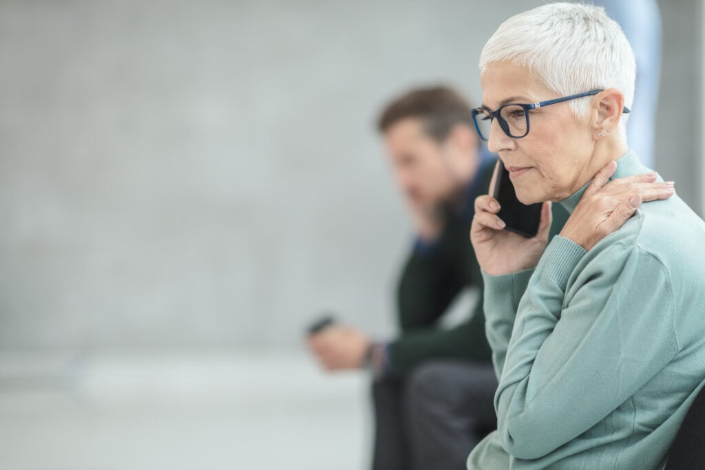 concerned older woman on phone, younger man in background