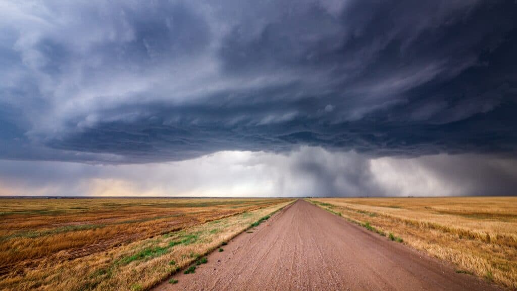 Dark storm clouds sit over an empty country road on the plains