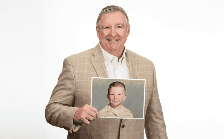 Photo of Jim Daly holding up a photo of himself as a child