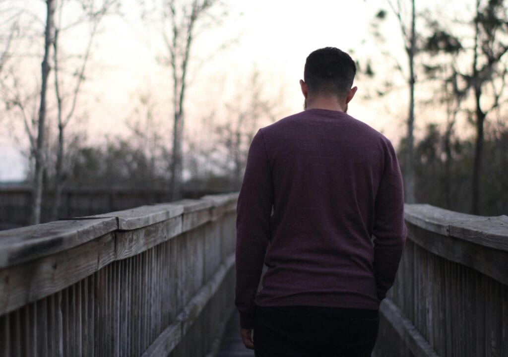 man walking away over bridge