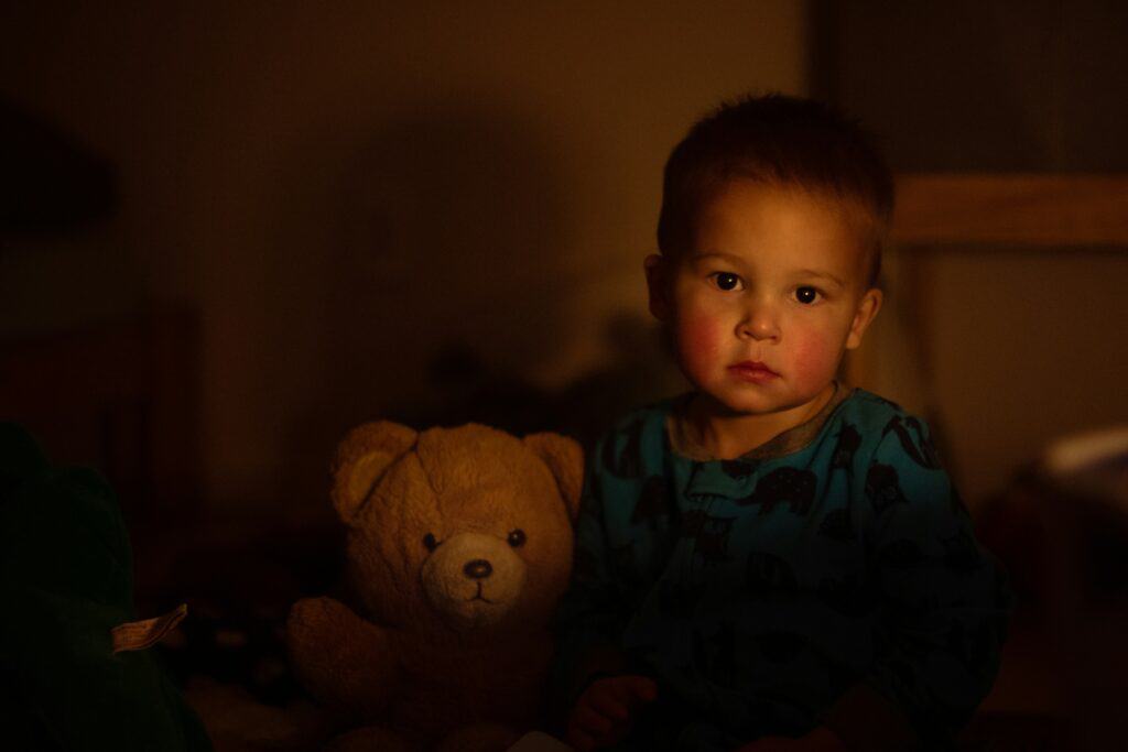 scared boy in dark with teddy bear