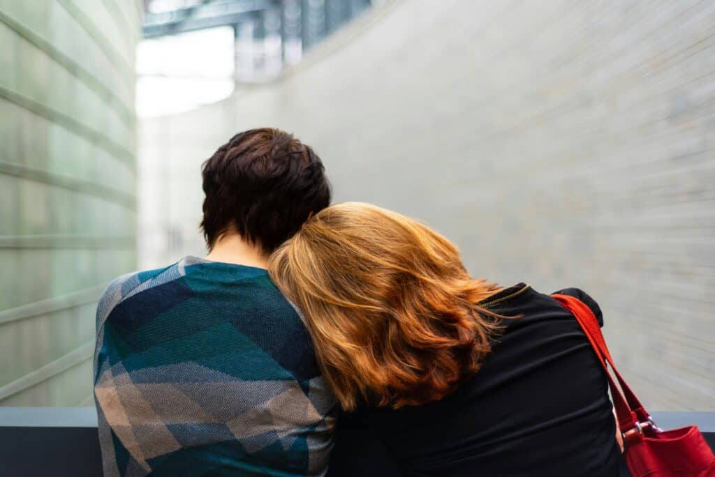 sad couple woman leaning on man's shoulder on bench