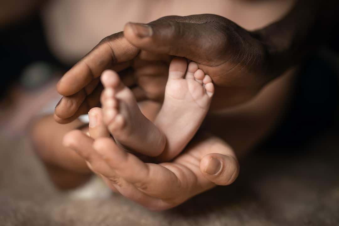 A pair of hands holding a newborn baby's feet.