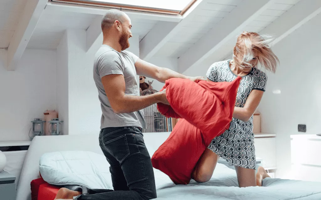 Adult Couple Having Fun In A Pillow Fight In Their Bedroom, having fun and flirting their way to a better marriage