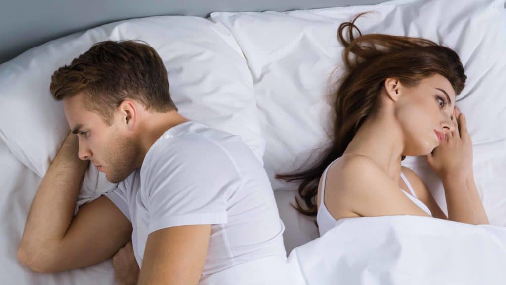 Sad couple in bed. Your sexual backstory affects your sex life.