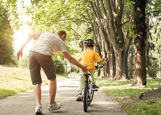 Father-teaching-son-to-ride-bike-and-pushing-bike-from-behind