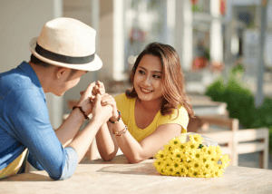 Asian-married-couple-holding-hands-at-restuarant-table-outside-with-flowers