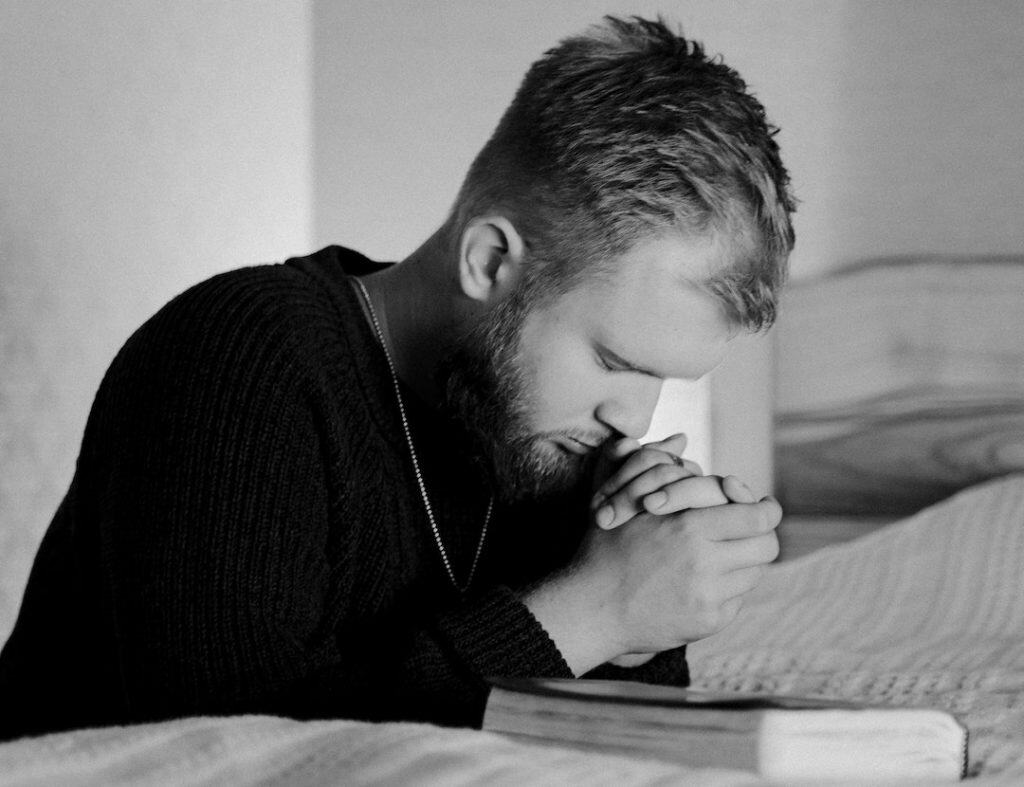 Photo of a man praying over his Bible.