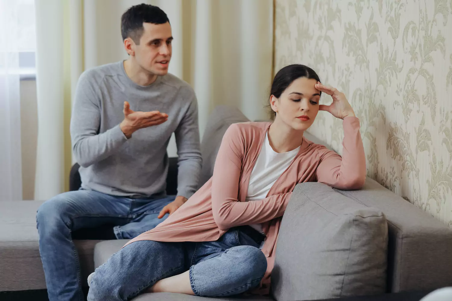 A young husband pleads his case with his wife while she holds her head in frustration. The wife wants better communication.