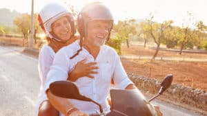 Mature-couple-laughing-together-riding-motorcycle