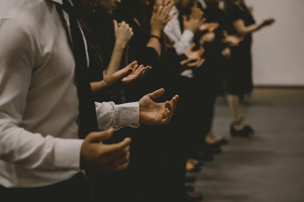 A group of people praying in church with palms up.