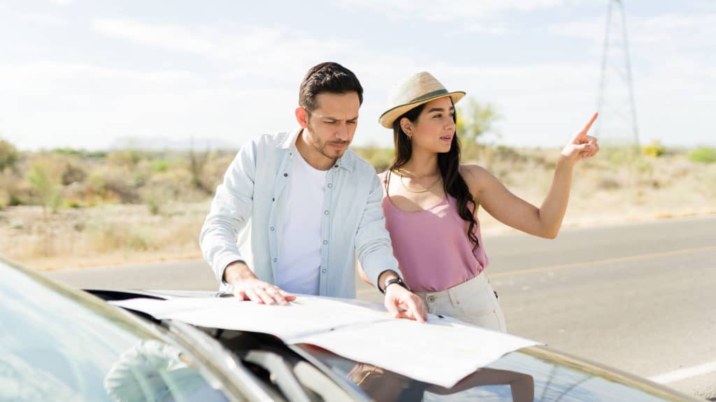 Confused-young-couple-looking-for-directions-on-a-road-map-by-car