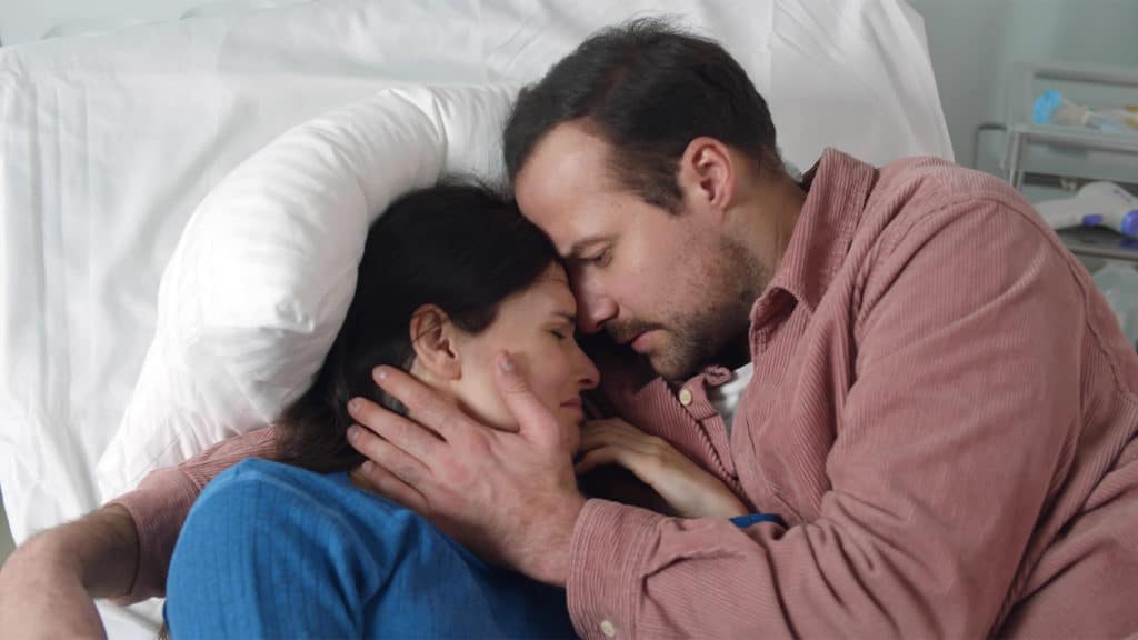 Husband-hugging-wife-with-terminal-illness-in-hospital-bed