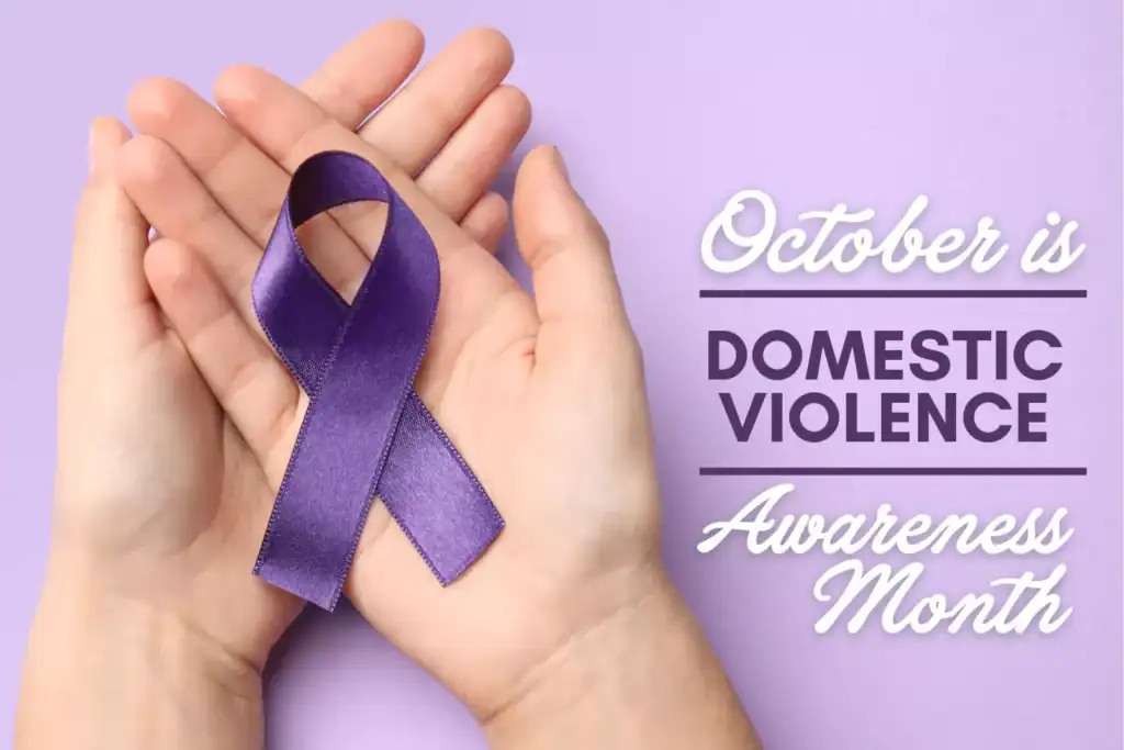 Hands cradling a purple ribbon for Domestic Violence Awareness Month in October
