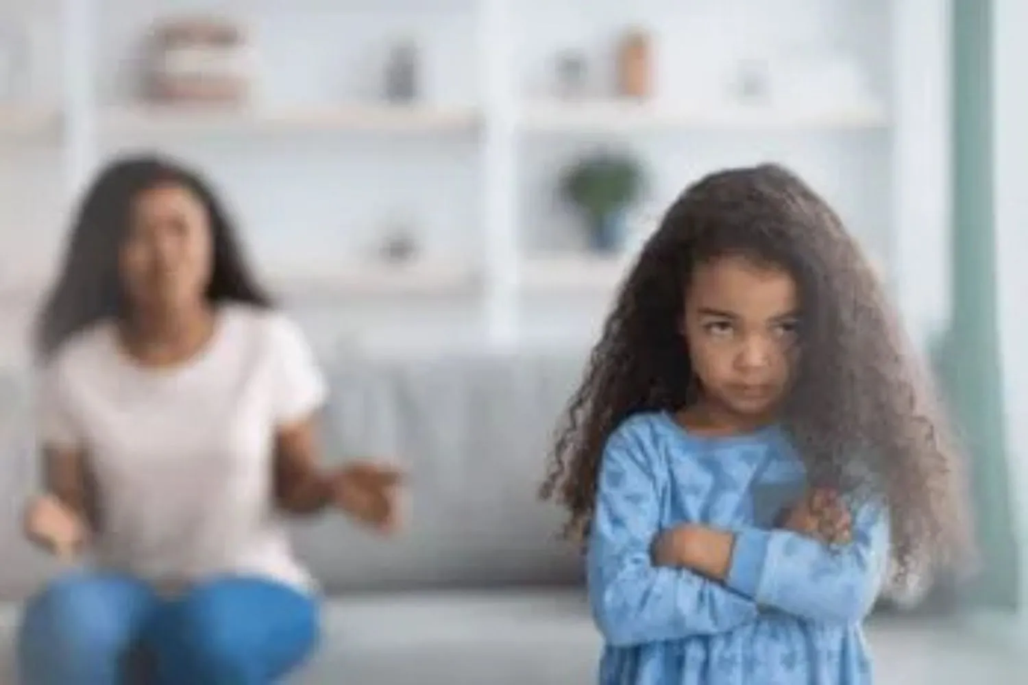 Mother sitting on the couch, reaching toward a petulant daughter