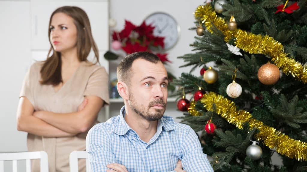 Husband-and-wife-with-holiday-stress-sitting-by-Christmas-tree