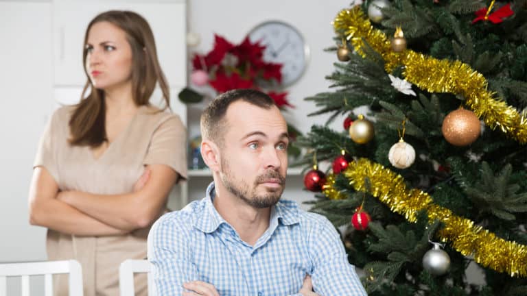 Husband-and-wife-with-holiday-stress-sitting-by-Christmas-tree