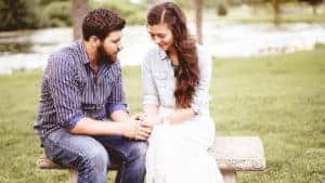 Young-husband-praying-with-his-wife-outside-on-bench © Wirestock Creators /Shutterstock.com