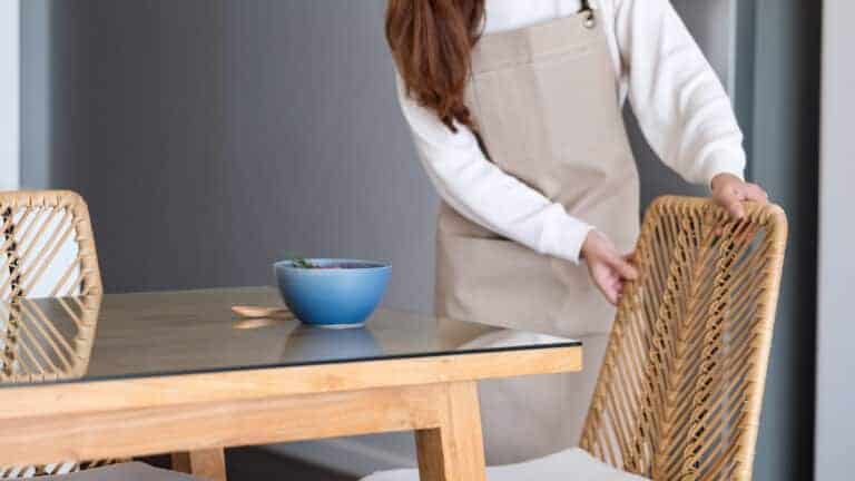 A woman preparing and setting dining table and chair at home.