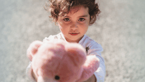 Small little girl sharing her teddy bear-generosity