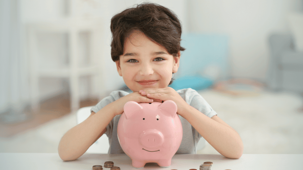 teaching our kids to manage money, this little boy with a piggy bank and a big smile is learning to manage his money.
