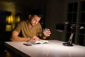 Young man studying at home drinking a glass of water