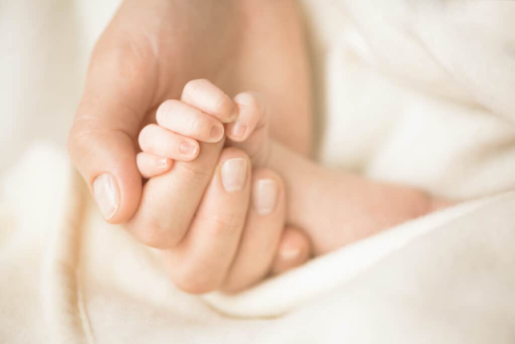 Female hand holding her newborn baby's hand. Mom with her child.