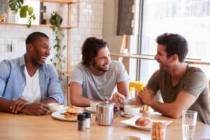 Three Male Friends Meeting For Lunch In Coffee Shop.