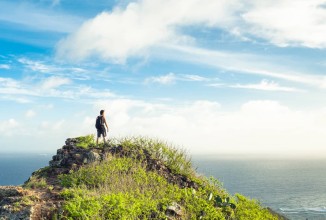 Freedom and adventure concept. Man on edge of a mountain looking out towards the horizon.