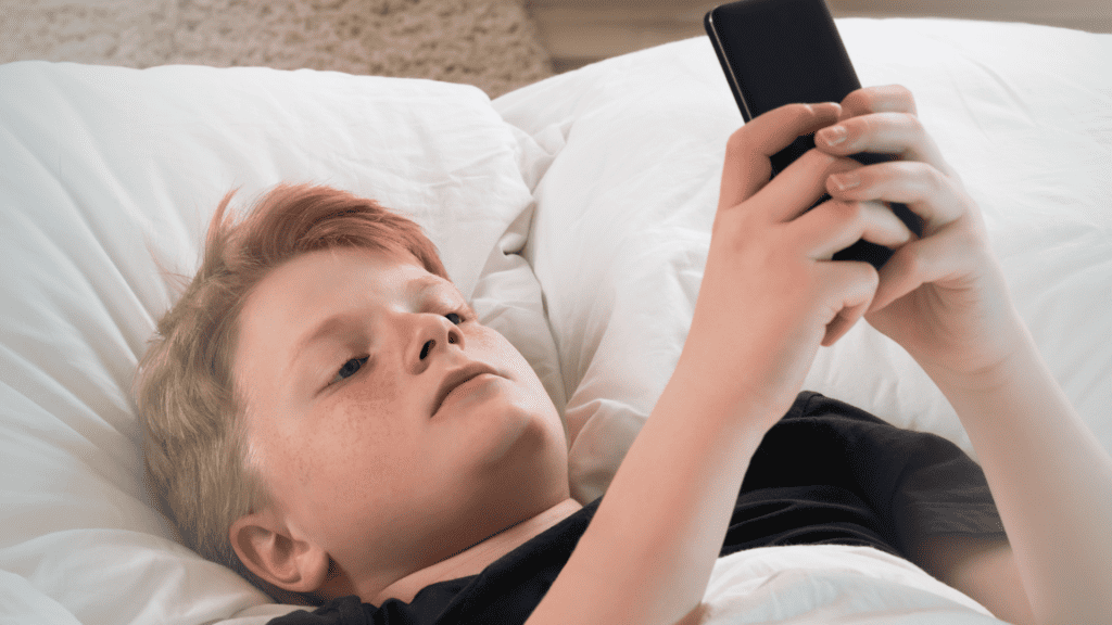 building trust with your teens in a digital age. Teenage boy laying on his bed looking at his phone.