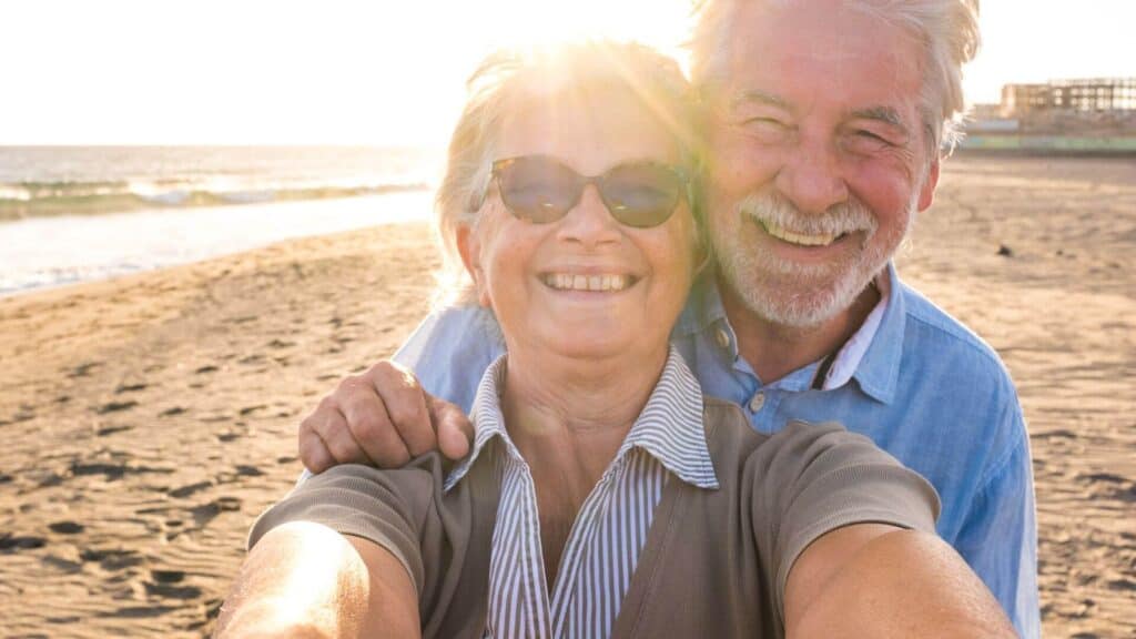 two empty nesters posing for a selfie on the beach