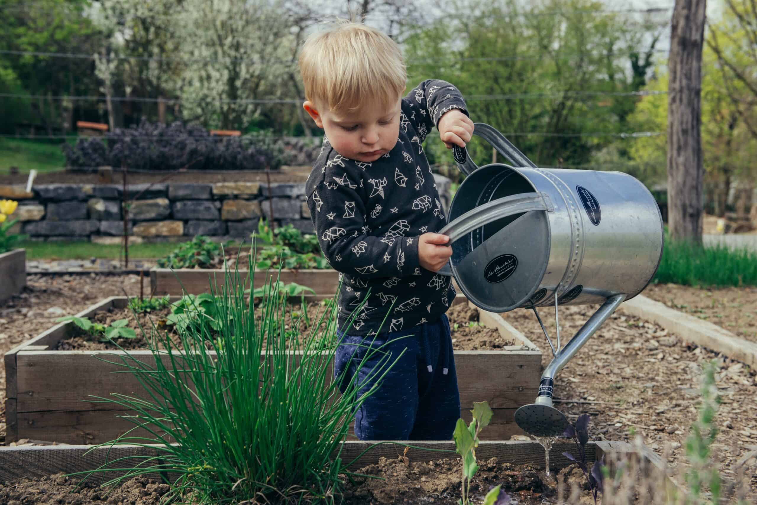 Kid with a watering can with his family during National Gardening Week