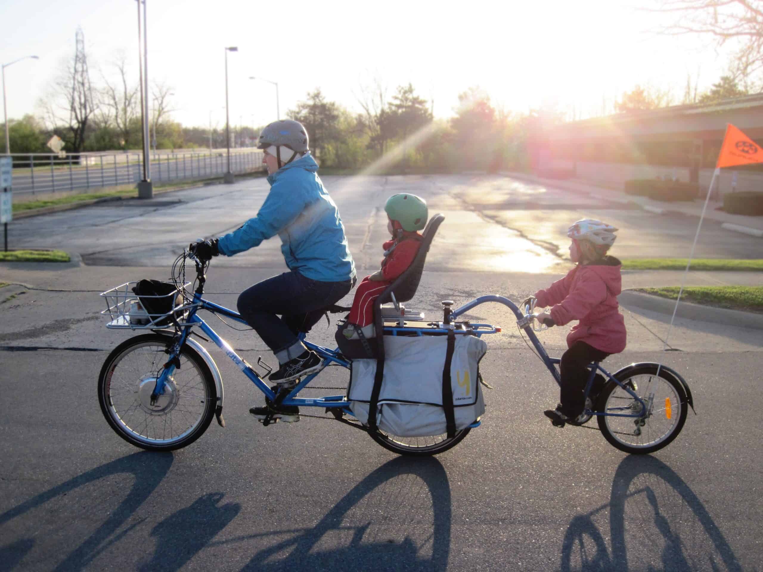 Father riding a tandem bike with his two children.