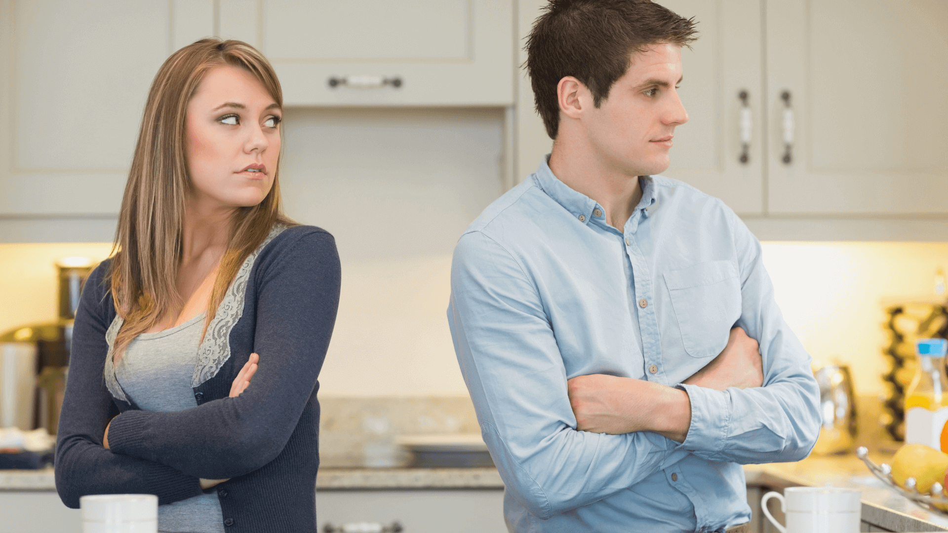 Married couple standing with their backs to each other with arms crossed. The woman looks over her shoulder at the man, wondering how to apologize to her spouse.